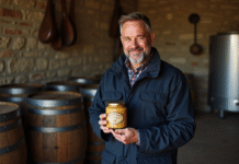 Producteur de foie gras tenant un pot dans un atelier rustique